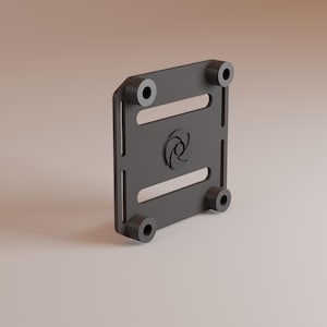 May include: A black metal plate with four black rubber feet and a logo in the center. The plate has two slots cut into it.