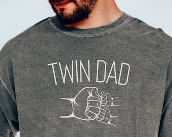 May include: A gray t-shirt with the text "Twin Dad" and a graphic of two hands clasped together in a fist bump.