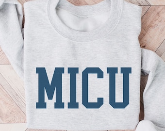 May include: A gray sweatshirt with the word "MICU" printed in dark blue on the front.