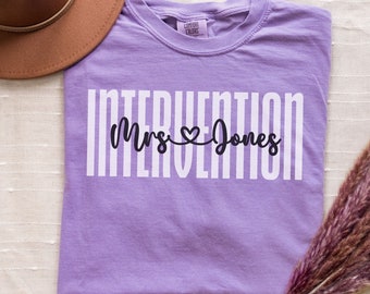May include: Purple t-shirt with white text that reads "Intervention Mrs. ♥ Jones".