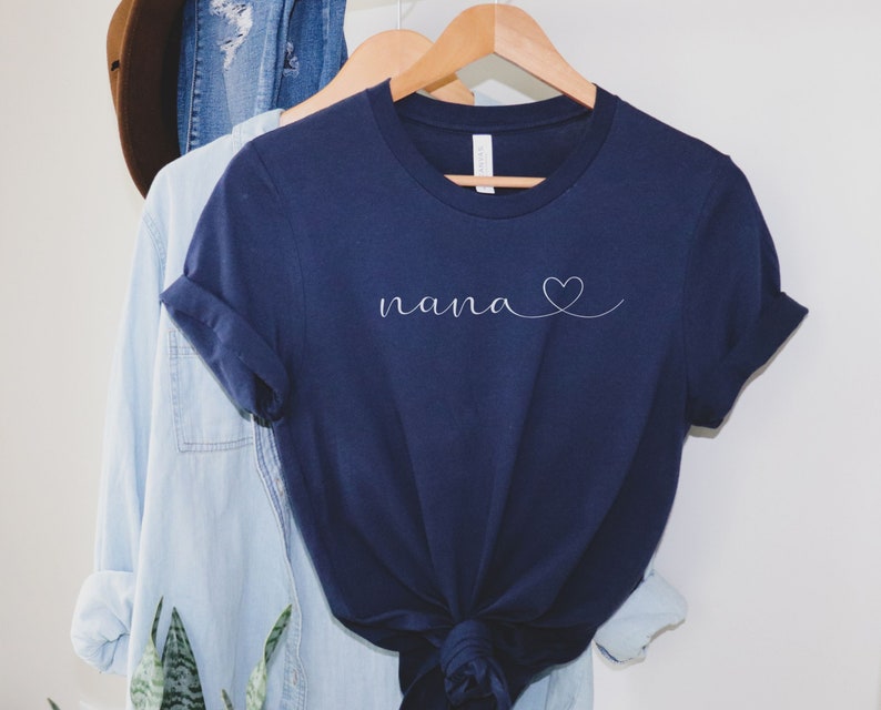 Peut inclure: Un t-shirt bleu marine avec le mot "nana" et un petit c&oelig;ur dessin&eacute; en blanc.