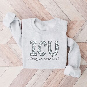 May include: A gray sweatshirt with the words "ICU intensive care unit" printed on the front. The letters are decorated with a floral pattern.