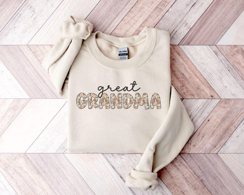 May include: A cream-colored sweatshirt with the text "great grandma" in floral letters.