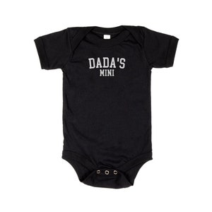 May include: Black short-sleeved baby onesie with the text "DADA'S MINI" in white.