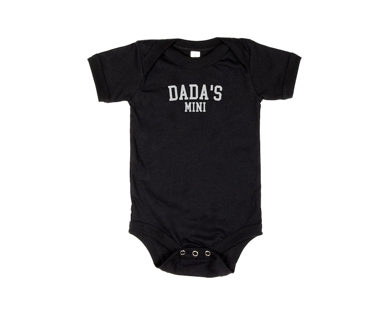 May include: Black short-sleeved baby onesie with the text "DADA'S MINI" in white.