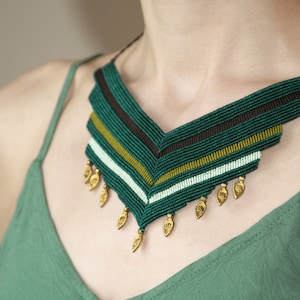 May include: A green and brown geometric patterned necklace with gold leaf accents.