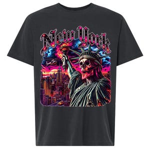 May include: A charcoal gray t-shirt featuring a graphic print of the Statue of Liberty with a skull face holding a torch. The design includes the text "New York" in a stylized font above a vibrant cityscape with a sunset, helicopters, and a taxi.