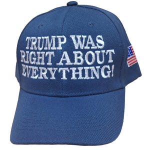 May include: A navy blue baseball cap with white embroidered text reading "TRUMP WAS RIGHT ABOUT EVERYTHING!". The cap has a curved peak and a small American flag patch on the side.