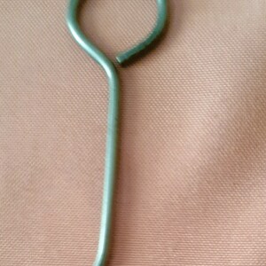 May include: A silver metal hook with a circular loop at the top and a hook at the bottom.