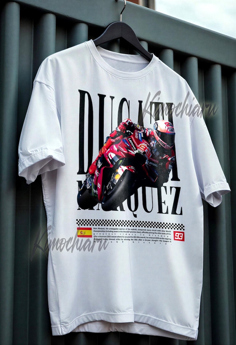 May include: White t-shirt featuring a graphic of a red and black motorcycle with the text "DUCATI MARQUEZ" in large black letters. Includes the number "93" and a Spanish flag.