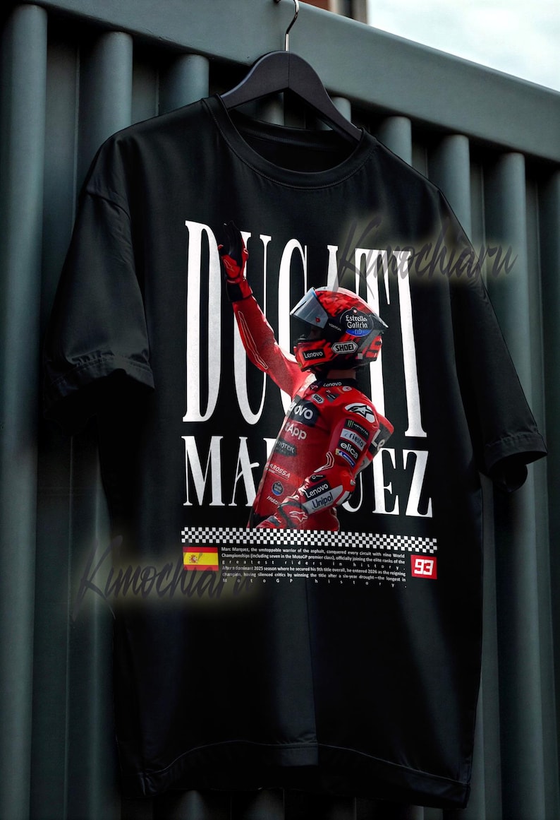 May include: Black t-shirt featuring a graphic of a racer in red racing gear, with the text "DUCATI MARQUEZ" in white. The racer is raising their arm in victory. The number "93" is visible. The shirt has a checkered flag design.