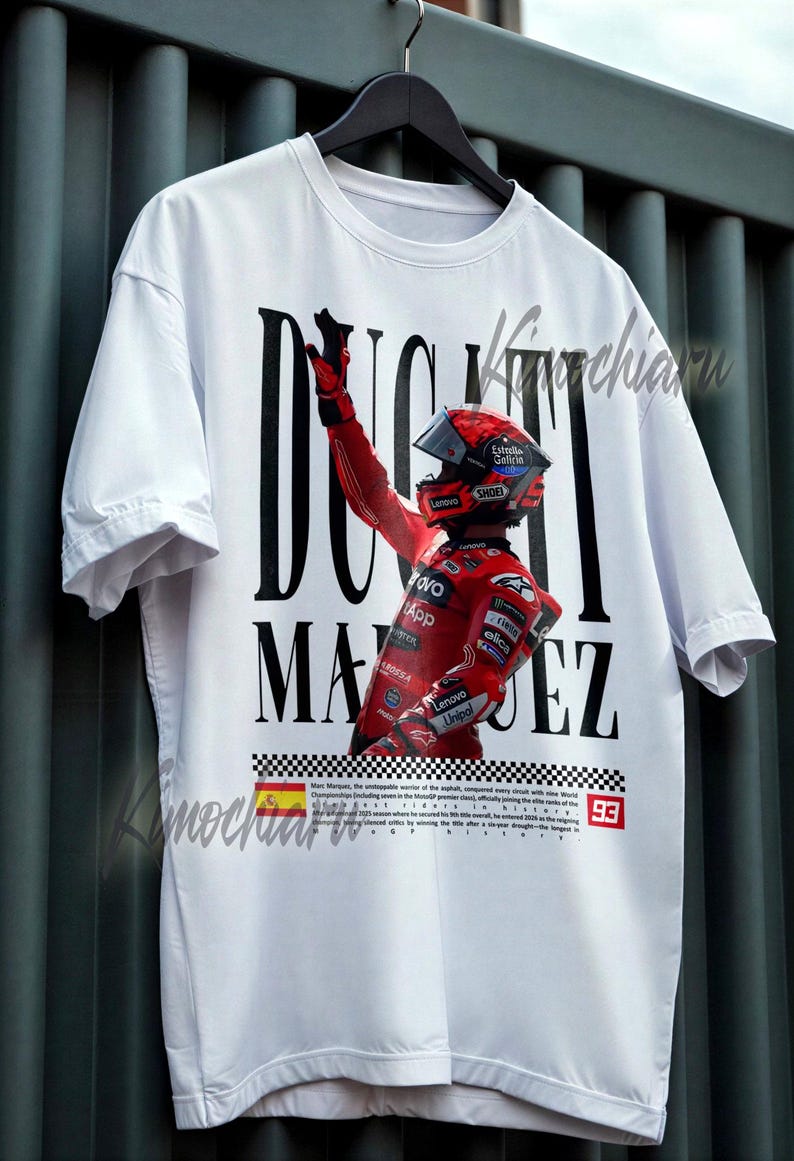 May include: White t-shirt featuring a graphic of a racer in a red racing suit and helmet, with the name "DUCATI MARQUEZ" in bold black letters. The shirt includes a checkered flag design and the number 93.