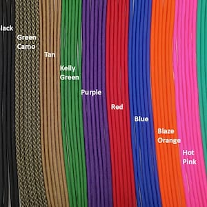 Op de afbeelding: Een verzameling verticale paracord-strengen in verschillende kleuren met de labels Black, Green Camo, Tan, Kelly Green, Purple, Red, Blue, Blaze Orange, Hot Pink en Teal. Elk koord heeft een gladde, gevlochten textuur naast elkaar.