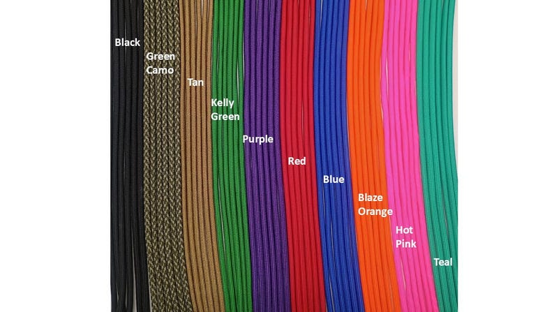 Op de afbeelding: Een verzameling verticale paracord-strengen in verschillende kleuren met de labels Black, Green Camo, Tan, Kelly Green, Purple, Red, Blue, Blaze Orange, Hot Pink en Teal. Elk koord heeft een gladde, gevlochten textuur naast elkaar.