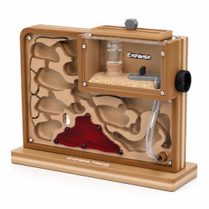 May include: A tan ant farm with a clear viewing window, featuring a sand-filled chamber and a red, gel-like area. The word "Expanse" is printed on the side. The design includes a water reservoir and a tube for access.