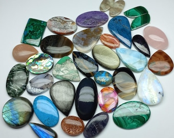 Peut inclure: Assortiment de cabochons de pierres précieuses colorées de formes et de tailles variées, notamment vert, bleu, violet, marron et blanc.