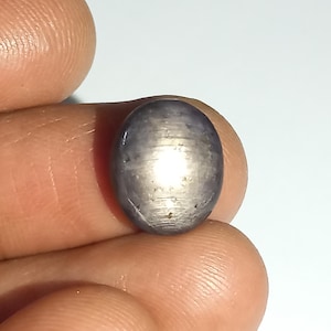 May include: A silvery-grey oval-shaped gemstone with a star-like pattern in the centre.