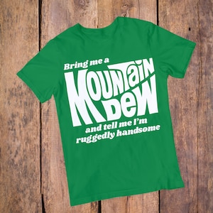 May include: Green t-shirt with white text that reads "Bring me a Mountain Dew and tell me I'm ruggedly handsome."