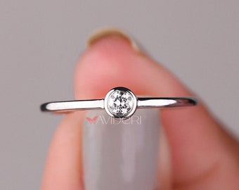 May include: A simple silver band ring with a single round clear stone in the center.