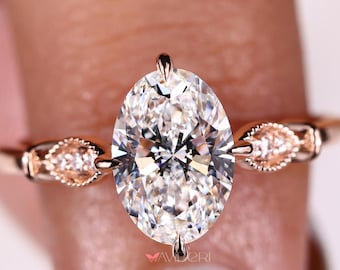 May include: A rose gold engagement ring with an oval-shaped diamond and delicate side stones. The ring is set on a thin band.