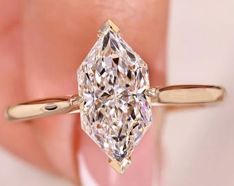 May include: A gold ring featuring a large, clear, marquise-cut diamond. The diamond is the focal point, with a brilliant, multifaceted surface. The ring's band is a simple, polished gold, and the diamond is set with gold prongs.