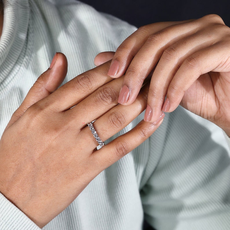The models hand slightly tilted, displaying the ring's side and the unique U prong setting. This angle provides a glimpse into the intricate design elements that make the band both beautiful and functi