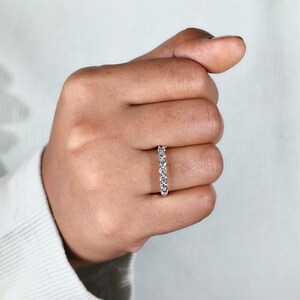 Close-up on the model hand, emphasizing the sparkling row of diamonds. The ring's brilliance is highlighted by natural lighting, showcasing the detail and quality of the lab-created diamonds.