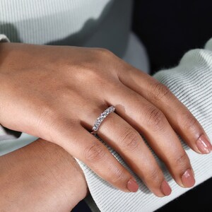 View of the ring on the models hand against a subtle background. The white gold band and the diamonds blend harmoniously, creating a stunning visual impact and evoking a sense of timeless elegance.