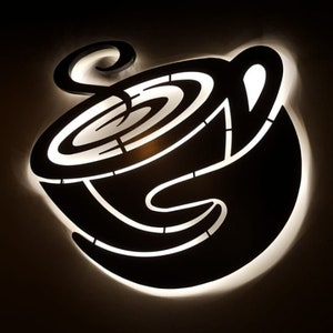 May include: A black and white silhouette of a coffee cup with steam rising from the top. The cup is lit from behind, creating a glowing effect.