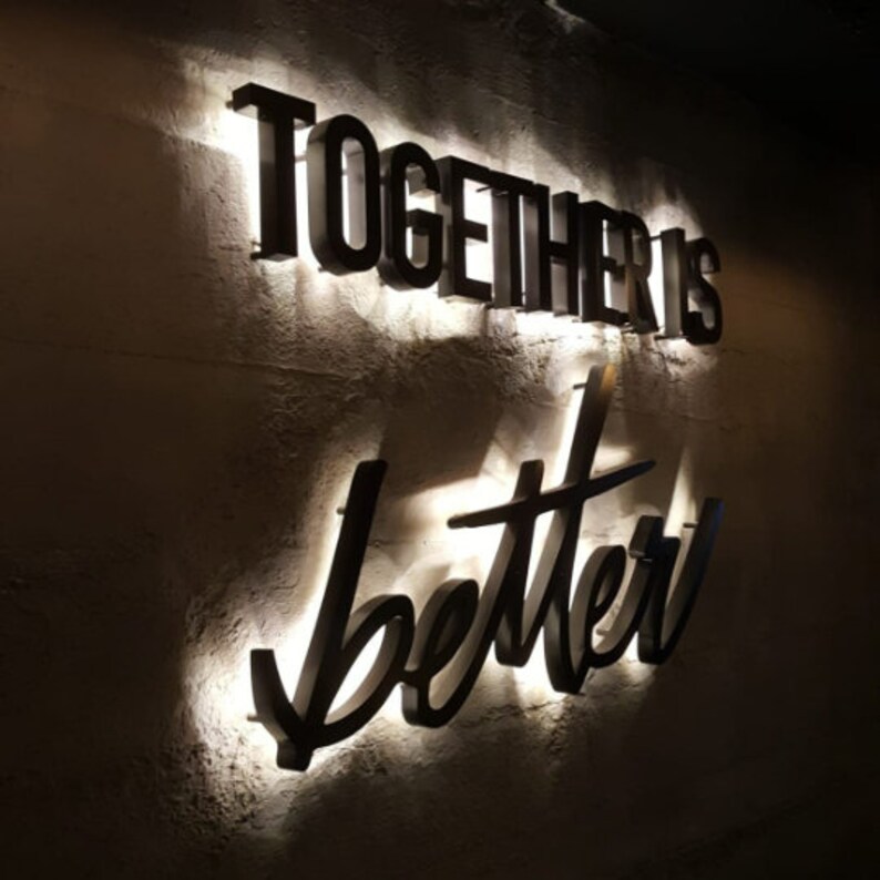 May include: A white wall with black lettering that reads "Together is better". The letters are illuminated with white light.