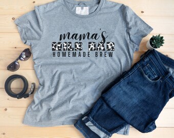 May include: Gray t-shirt with the text "mama's milk bar homemade brew" in black lettering with a cow print design.