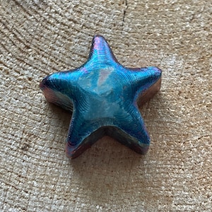 May include: A blue and purple iridescent glass star ornament with a textured surface.