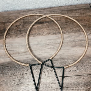 May include: Two brown rope hoops and three black metal hoops, all lying on a wooden surface.