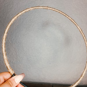 May include: A brown rope wrapped around a black metal hoop. The hoop is circular and has a diameter of approximately 12 inches.