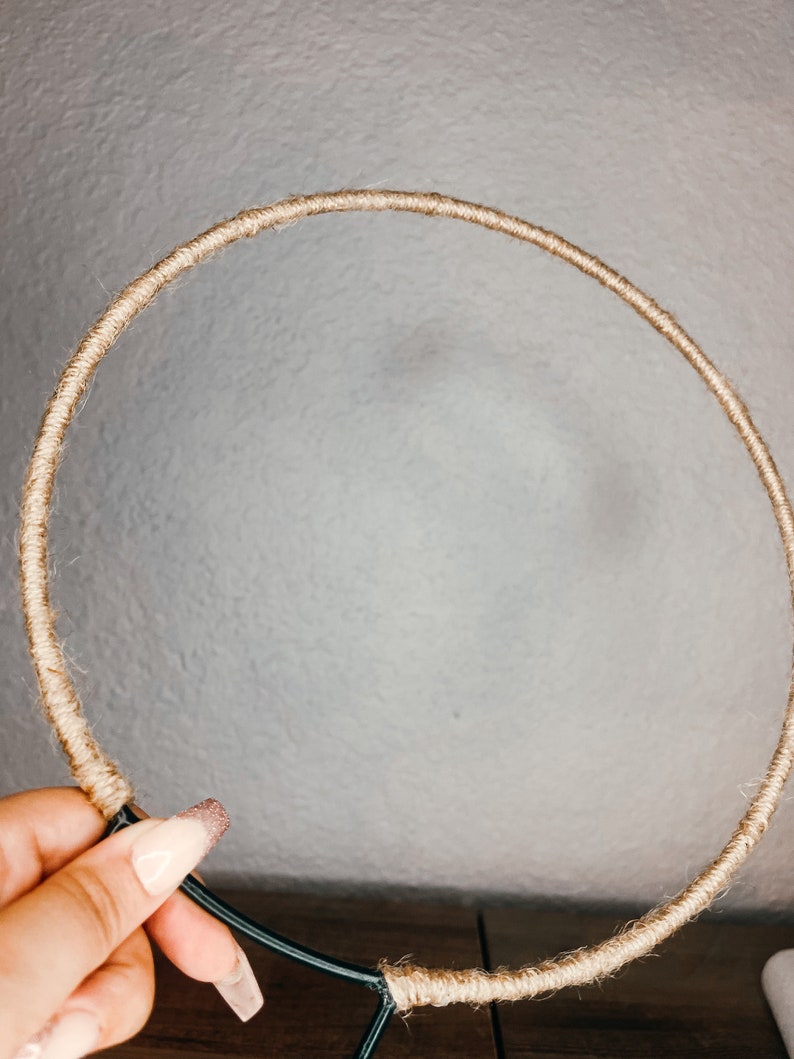 May include: A brown rope wrapped around a black metal hoop. The hoop is circular and has a diameter of approximately 12 inches.