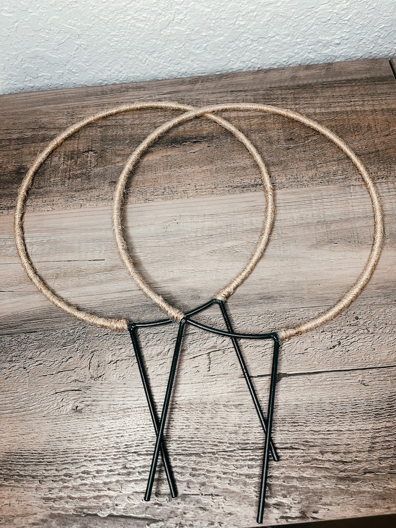 May include: Two brown rope hoops and three black metal hoops, all lying on a wooden surface.