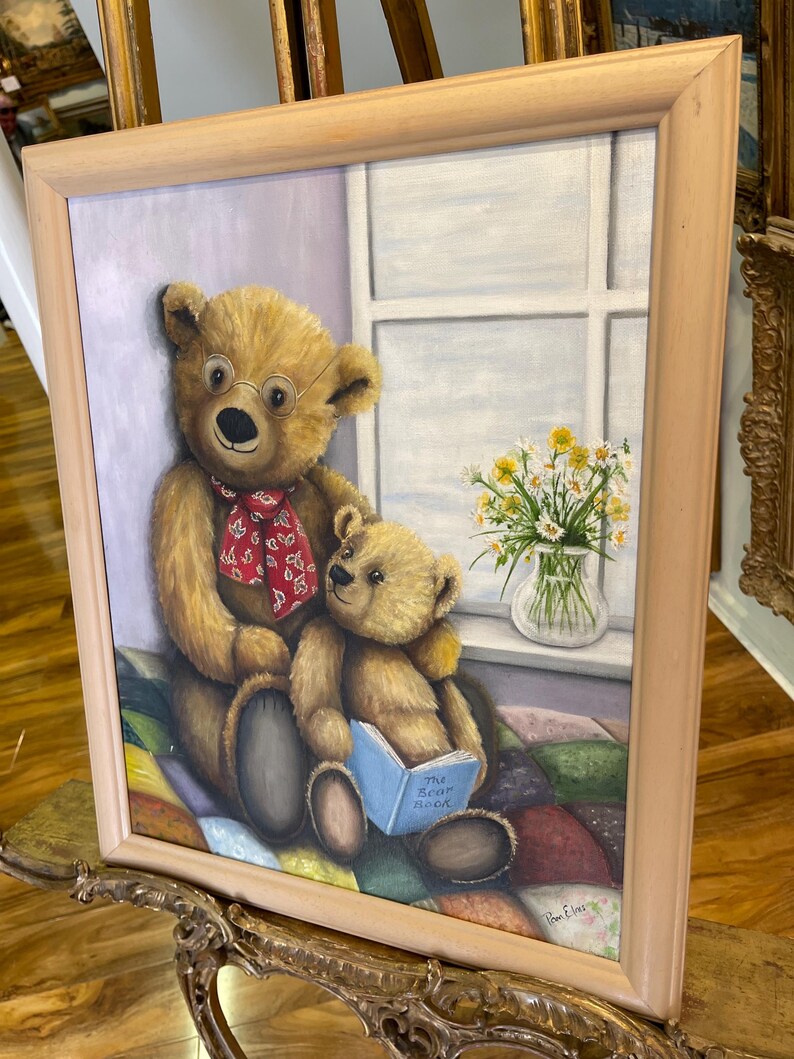 Puede incluir: Una pintura de dos osos de peluche sentados en una colcha de retazos. El oso m&aacute;s grande lleva gafas y una bufanda roja. El oso m&aacute;s peque&ntilde;o sostiene un libro azul que dice "The Book Nook".