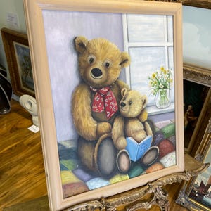 Puede incluir: Una pintura enmarcada de dos osos de peluche, uno con gafas y una bufanda roja, sentados en una colcha de retazos colorida. El oso m&aacute;s grande sostiene un oso m&aacute;s peque&ntilde;o y lee un libro titulado "The Very Busy Spider".