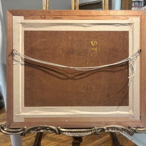 Puede incluir: La parte posterior de una pintura enmarcada con un marco de madera y un borde dorado. La parte posterior de la pintura est&aacute; hecha de cart&oacute;n marr&oacute;n. La pintura est&aacute; colgada en una pared.