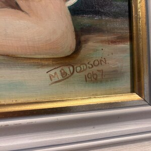 Puede incluir: Primer plano de una pintura con marco dorado. La pintura est&aacute; firmada "M.B. Dodson" y fechada "1967".