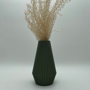 Può includere: Un vaso in ceramica verde scuro con un design geometrico e una texture a coste. Il vaso è riempito con erba della pampa secca.