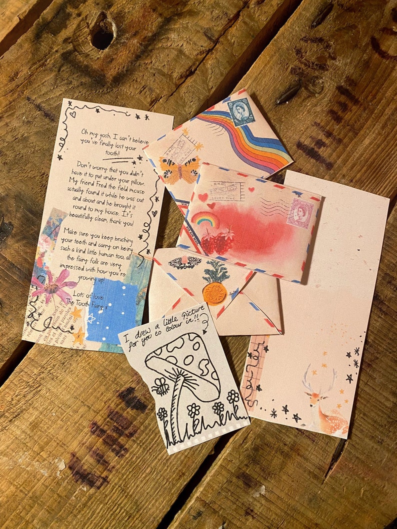 May include: A collection of colorful envelopes with handwritten notes and drawings. The envelopes feature rainbows, hearts, stars, and a deer. One note says "I drew a little picture for you to color in!!!" and includes a drawing of a mushroom.