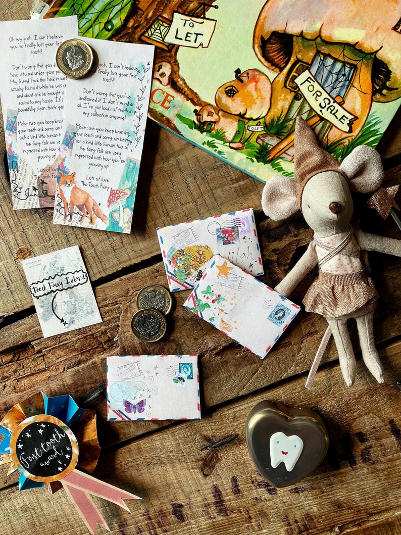 Puede incluir: Un kit de hada de los dientes con un premio de hada de los dientes, una peque&ntilde;a caja en forma de coraz&oacute;n con un dise&ntilde;o de diente, sobres, monedas y una peque&ntilde;a mu&ntilde;eca de rat&oacute;n con un vestido marr&oacute;n y un sombrero. Los sobres tienen notas escritas a mano e ilustraciones.