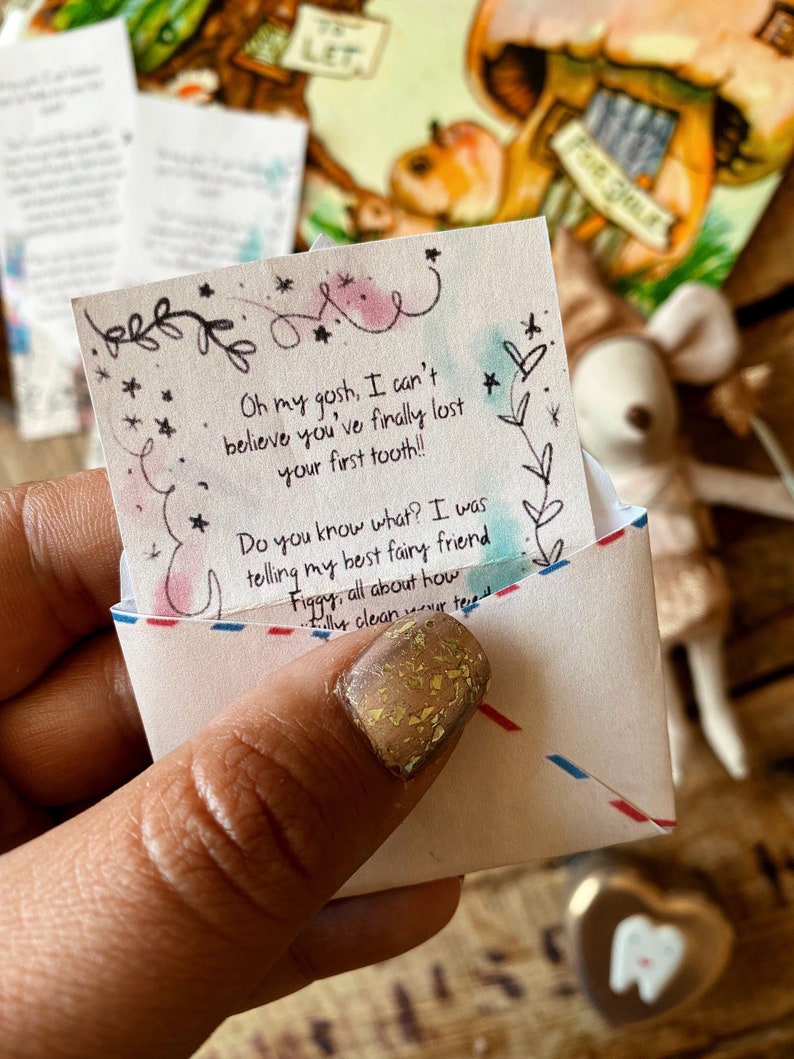 Puede incluir: Un peque&ntilde;o sobre blanco con una nota escrita a mano en su interior. La nota dice "Oh my gosh, I can't believe you've finally lost your first tooth!! Do you know what? I was telling my best fairy friend Figgy, all about how..." El sobre est&aacute; decorado con estrellas y un dise&ntilde;o floral.