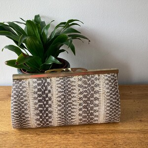 May include: A white and grey snakeskin clutch bag with a gold metal clasp.