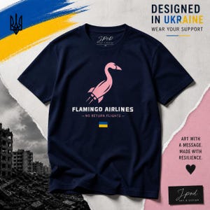 Op de afbeelding: Marineblauwe t-shirt met een roze flamingo-ontwerp, de tekst "FLAMINGO AIRLINES - NO RETURN FLIGHTS" en een Oekraïense vlag. Het shirt toont ook de tekst "DESIGNED IN UKRAINE" en "WEAR YOUR SUPPORT".
