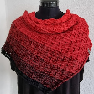 May include: A red and black crocheted shawl with a textured pattern. The shawl is draped over a black mannequin.