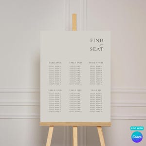 May include: A light beige rectangular seating chart sign displayed on a wooden easel. The sign features the text FIND YOUR SEAT in the upper right corner, followed by six columns labelled TABLE ONE through TABLE SIX, each with ten lines for guest names.