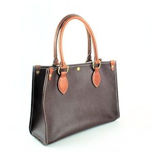 May include: A brown leather tote bag with brown leather handles and gold hardware.