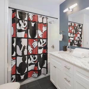 Può includere: Una tenda da doccia con un motivo a griglia ripetuto di Topolino in nero, bianco e rosso. Il design è composto da vari pannelli in primo piano che mostrano il viso, le orecchie e le mani guantate di Topolino per un look grafico.